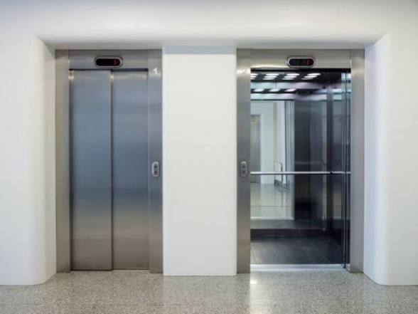 Ascenseurs en acier brossé dans un hall d'immeuble aux murs blancs